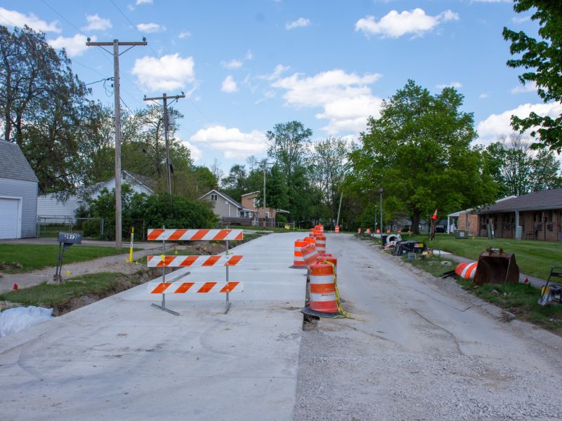 Construction barrels line a new concrete street