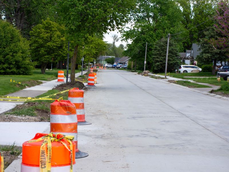 Construction barrels line a new concrete street in Waynedale