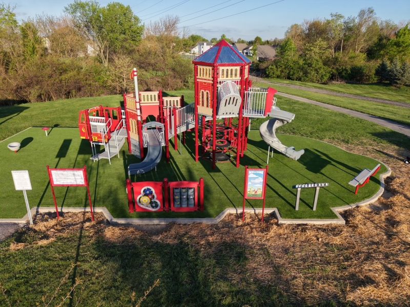 Image of completed playground, featuring a bright red firetruck and other fire-themed equipment